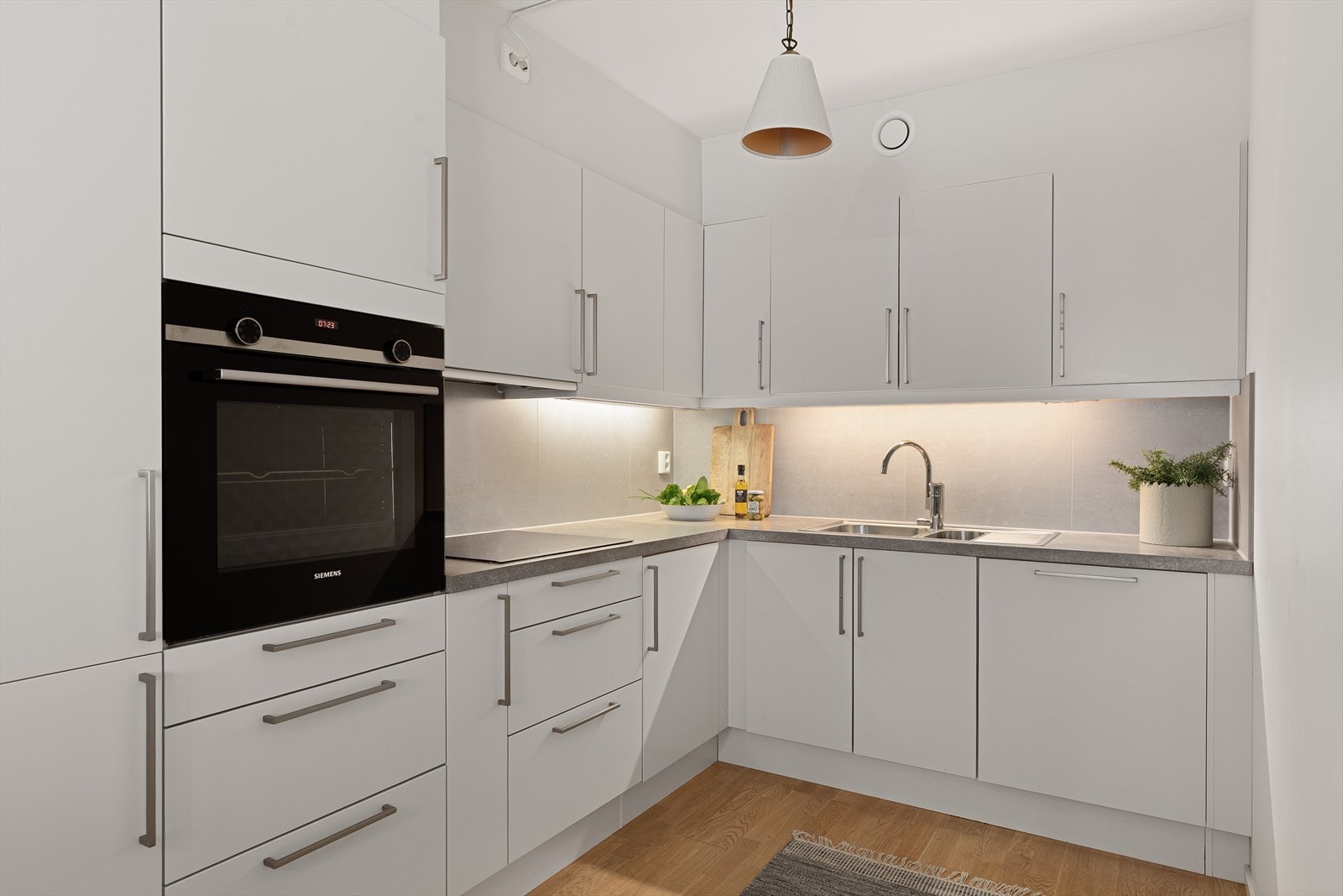 Innredningen er fra HTH med hvite, glatte fronter, og består av både over- og underskap med belysning under overskap. Galleribilde