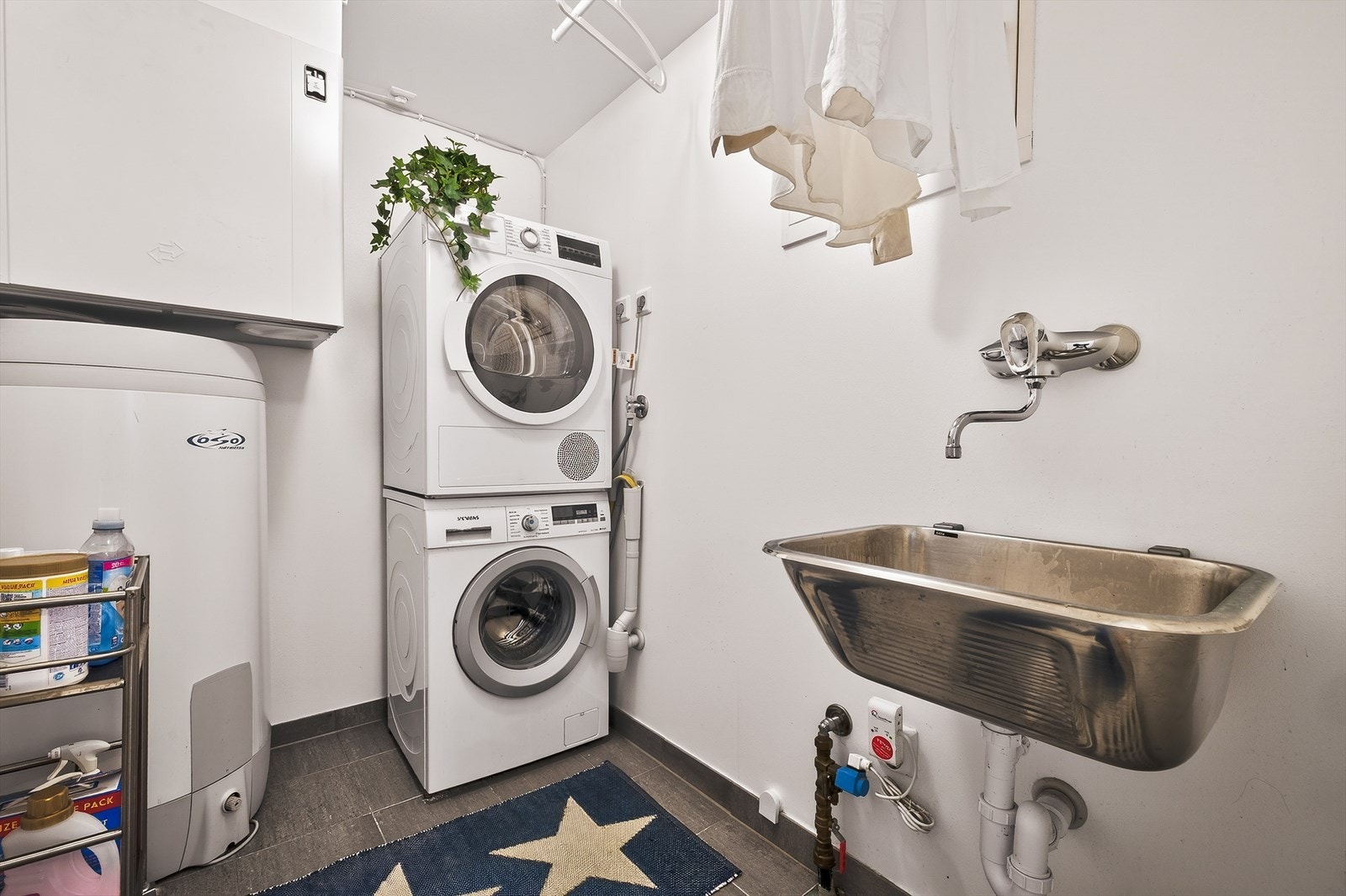 Praktisk vaskerom med opplegg for vaskemaskin/tørketrommel. Gulv er flislagt. Galleribilde