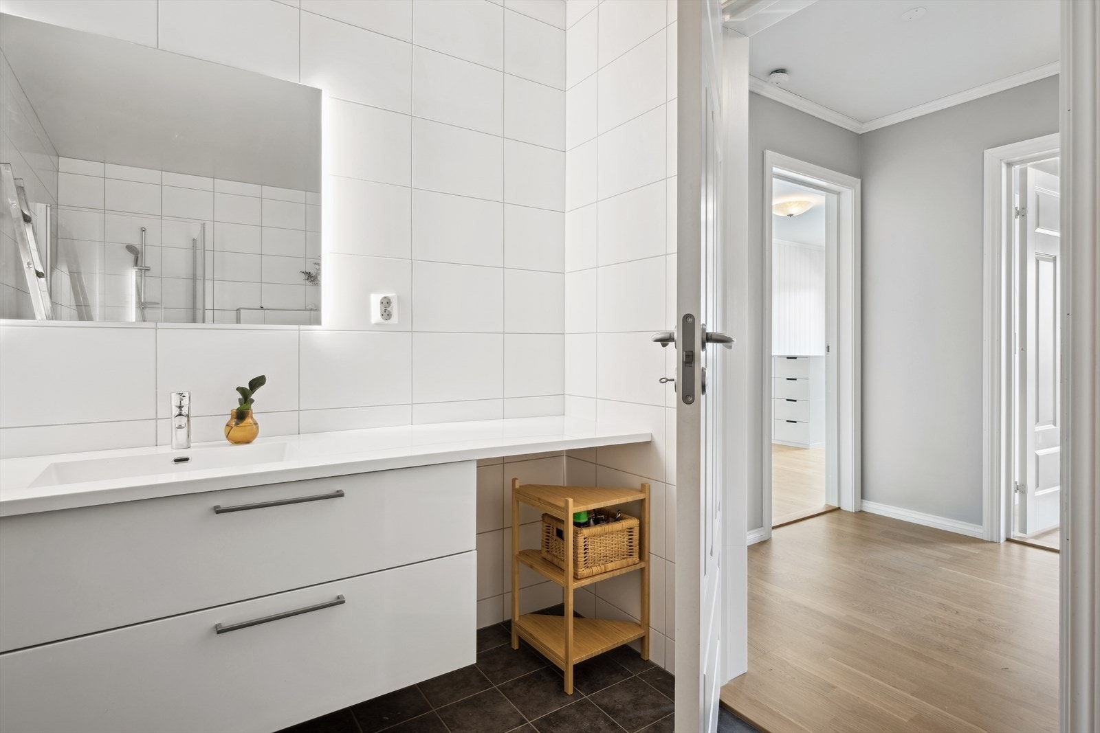 Badet er innredet med servant i hel benkeplate med dobbel skuffeinnredning under deler av benkeplaten. Vegghengt speil med integrert lys bak, dusjhjørne med innfellbare vegger og veggmontert toalett. Det er balansert ventilasjon i rommet. Galleribilde