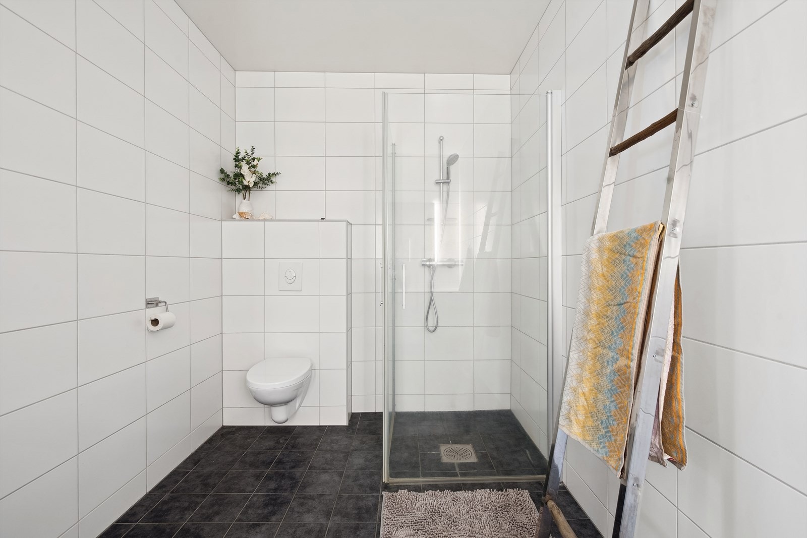 Baderommet i sokkeletasjen er flislagt på vegger og gulv. Rommet varmes opp med elektrisk gulvvarme. Det er registrert svertesopp i silikonfuge i dusjsonen, så det bør skiftes silikonfuge. Galleribilde