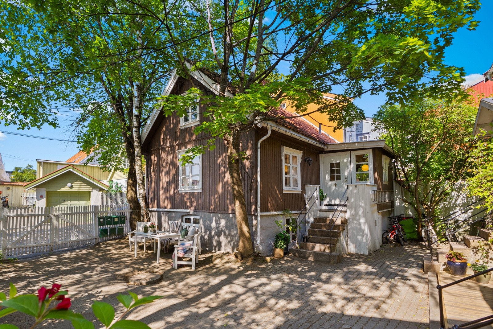 Skjermet bakgård med sitteplass i skyggen av trær og grønne omgivelser. Galleribilde