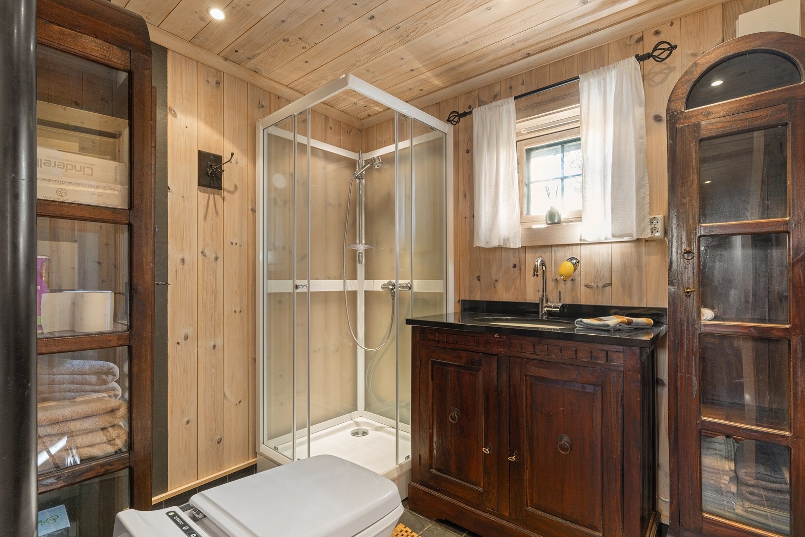 Hytta byr på flislagt bad med elektriske varmekabler i gulvet. Vegger og himling har trepanel, og rommet er utstyrt med servantinnredning, elektrisk forbrenningstoalett og dusjkabinett. Galleribilde