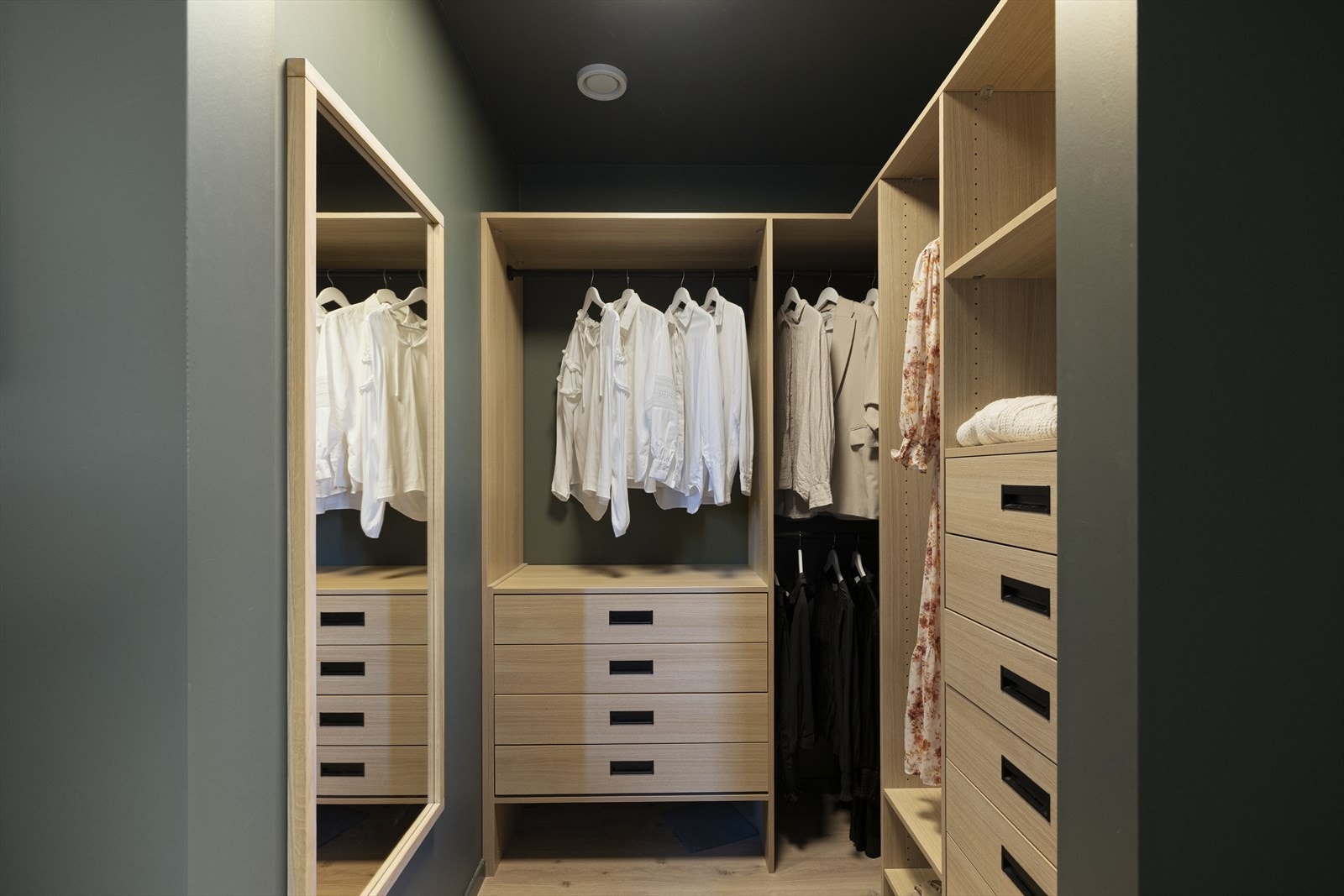 Garderoben har et stort hjørneskap med skuffer, hyller og klesoppheng Galleribilde