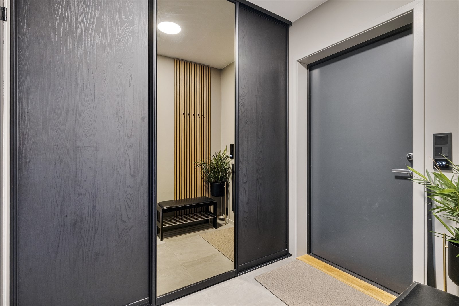 Yttertøyet ryddes enkelt bort i en plassbygd skyvedørsgarderobe med sorte fronter, stort speil og mye oppbevaring. Galleribilde