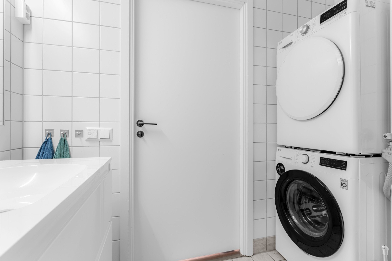 Badet inneholder vegghengt servantskap med heldekkende servant og ett-greps armatur, speil, overlys og stikkontakt over servant, dusjkabinett, toalett og opplegg for vaskemaskin. Galleribilde