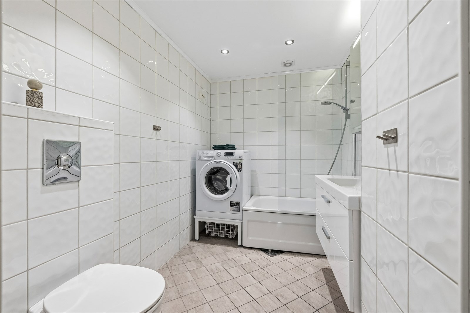 Rommet har varmekabler i gulv, veggmontert toalett og servant med speilskap og belysning. Galleribilde