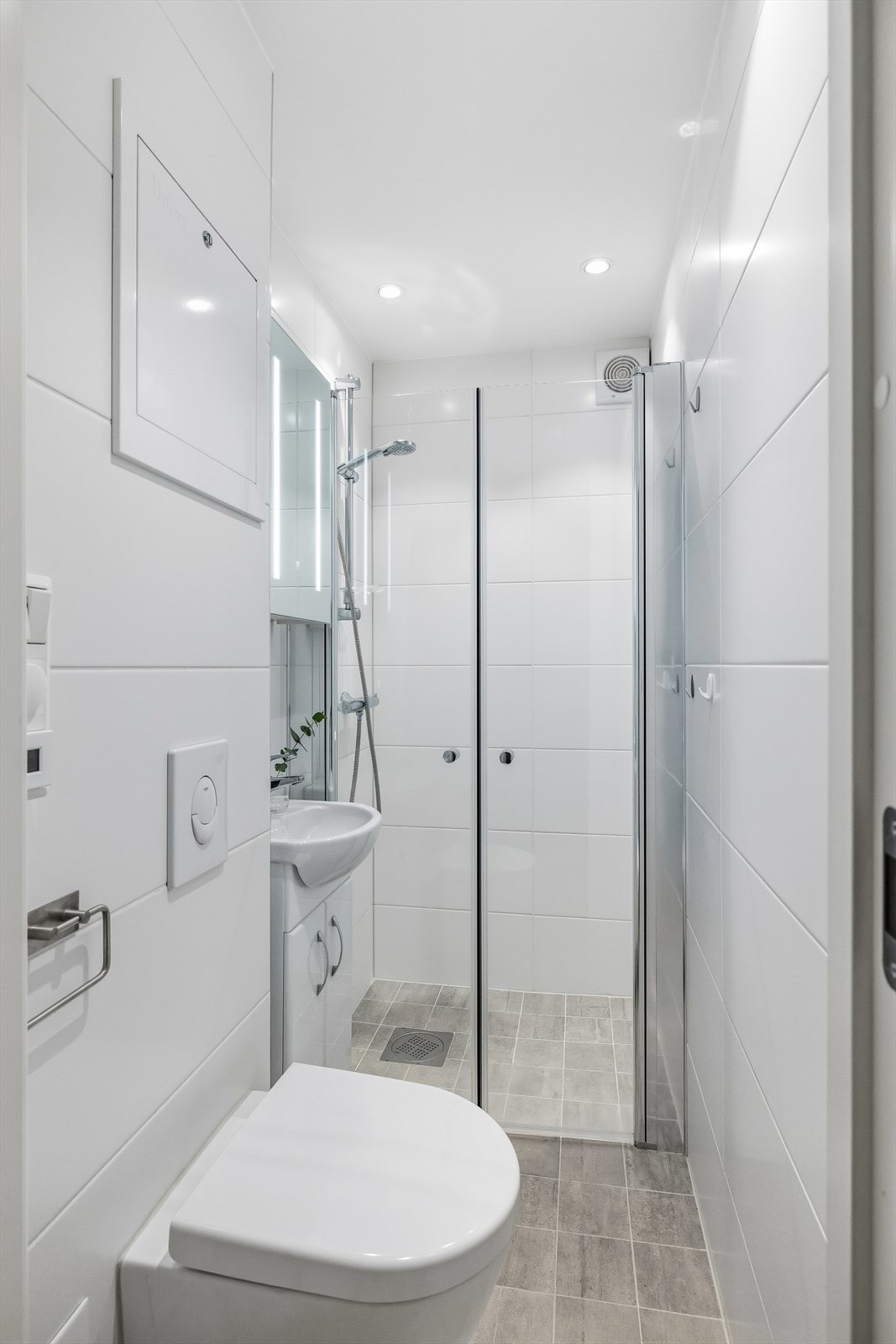 Moderne baderom fra 2024 med varmekabler i gulv, downlights og lyse flisflater. Galleribilde