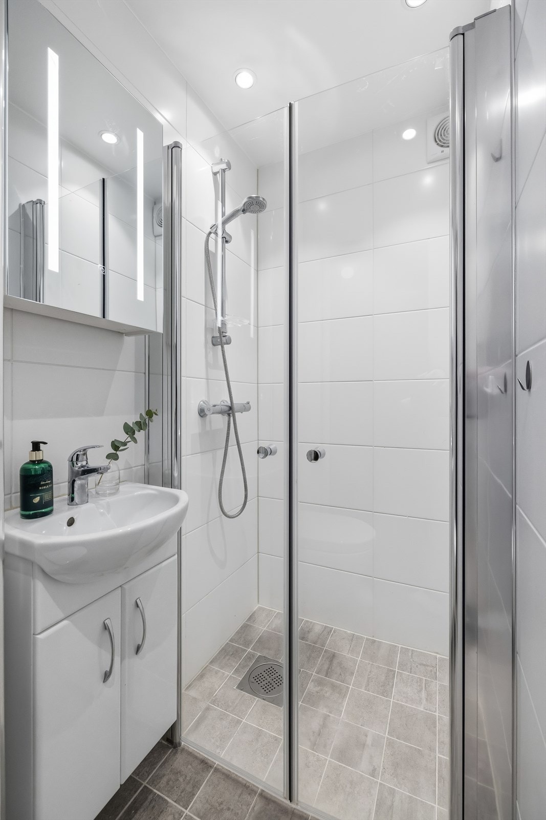 Badet har dusjhjørne med svingdører og servantskap med speil. Galleribilde