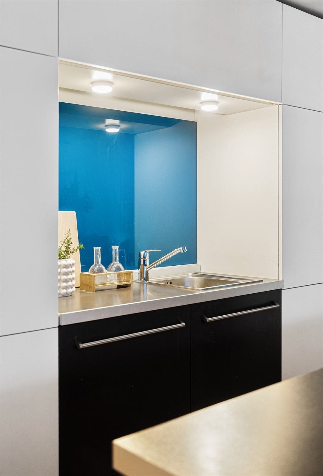 Praktisk nisje med vask, god belysning og glassplate over benken. Galleribilde