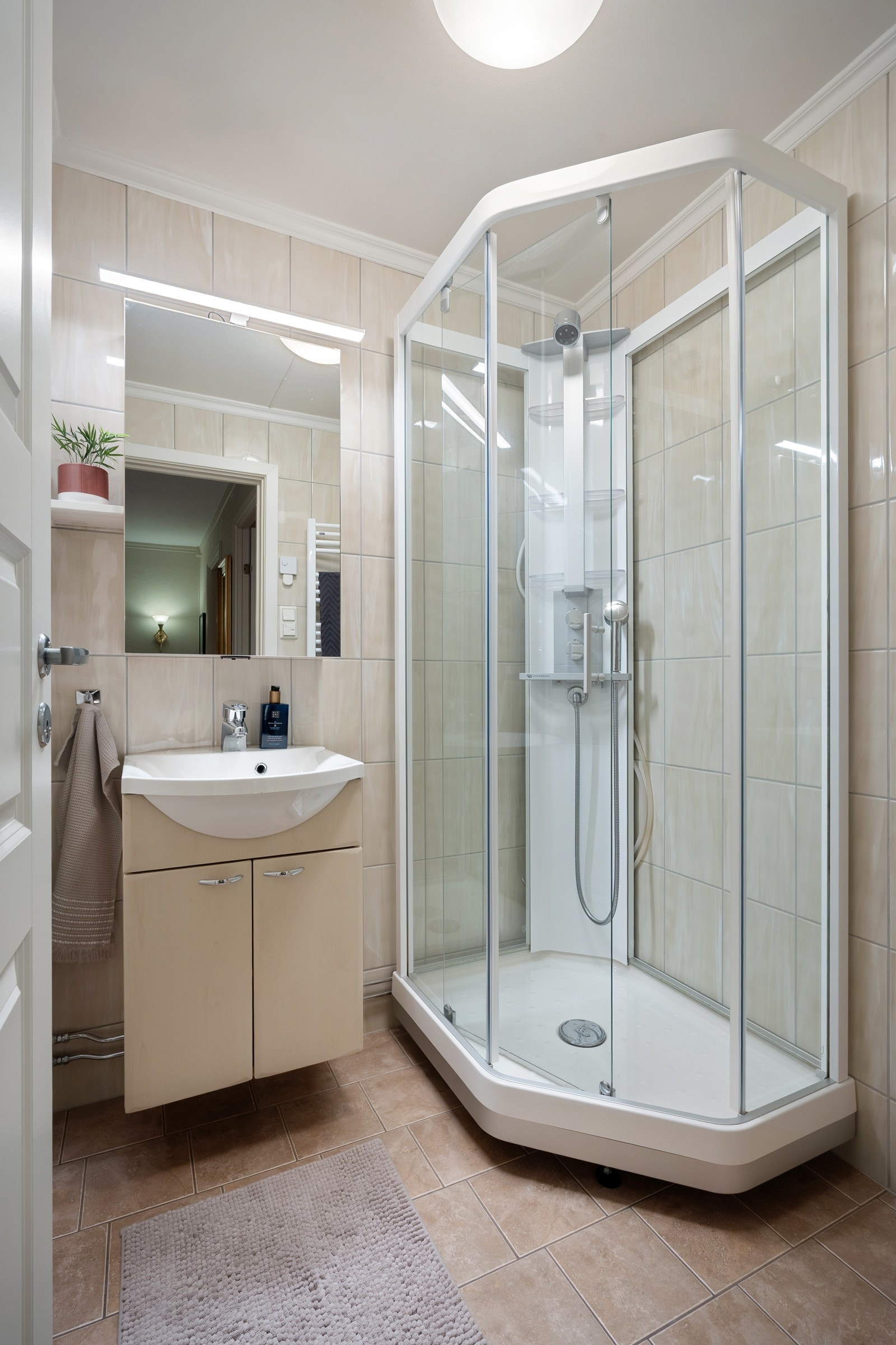 Flislagt bad, utstyrt med dusjkabinett, baderomsinnredning og speil. Galleribilde