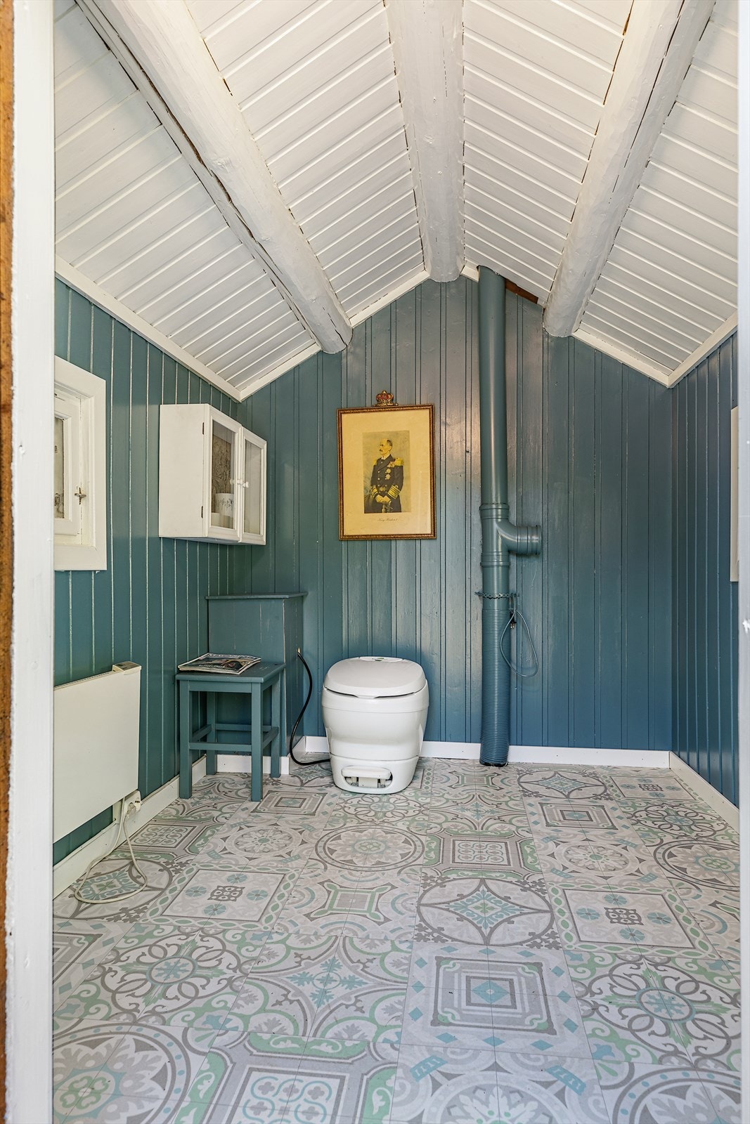 Pen utedo med tradisjonelt preg, oppusset med panelvegger i mørk blåtone og flismønstret gulvbelegg. Galleribilde