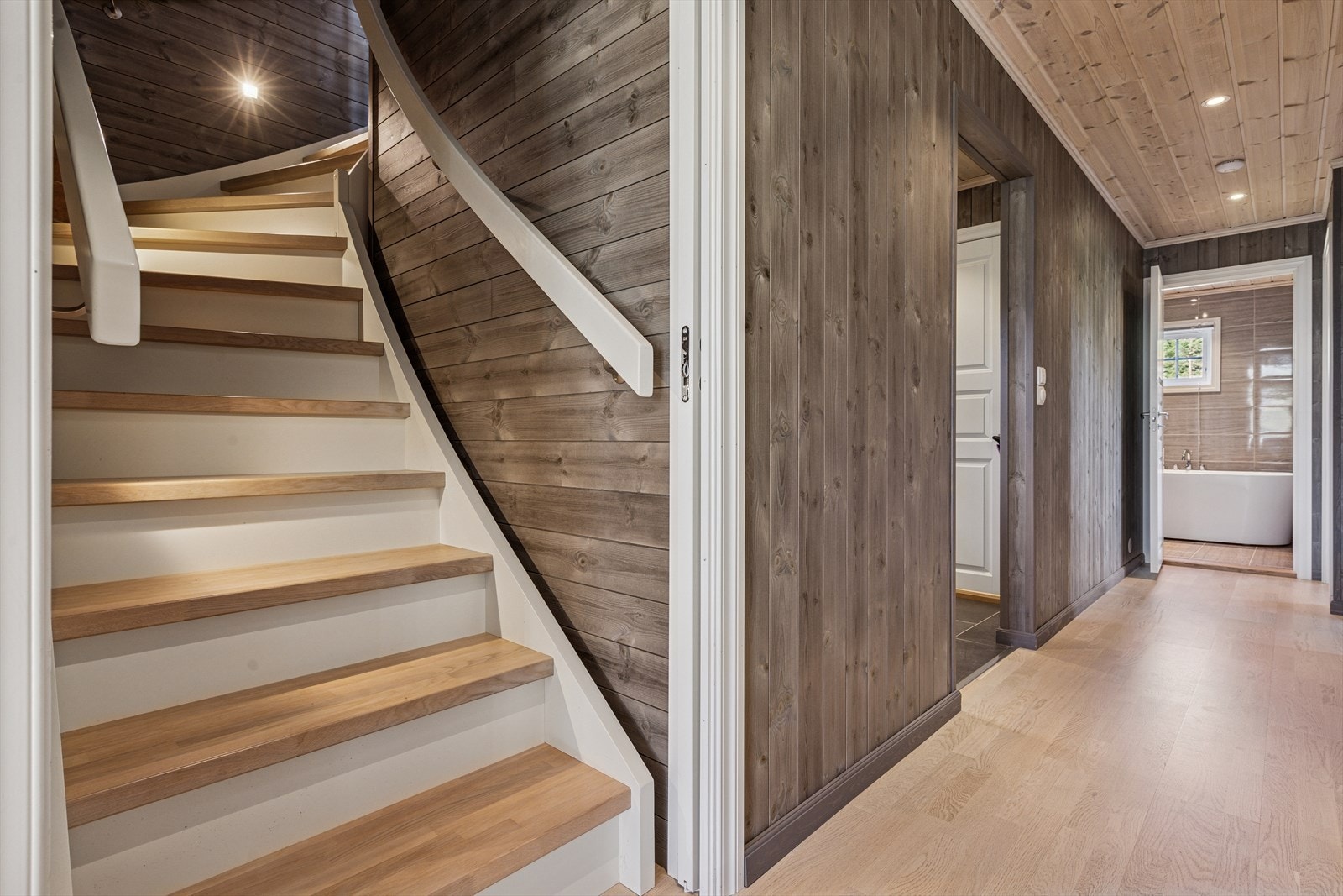 Lys og stilren trappeoppgang som binder etasjene sammen med god takhøyde. Her er det spoter i veggen som lyser opp trappen. Galleribilde