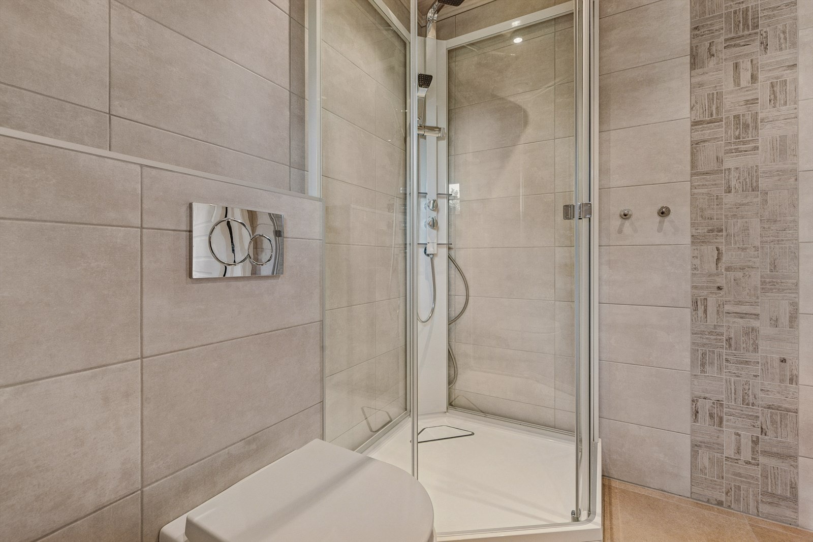 Bad nr 2 er også fliselagt, med veggmontert toalett og dusjkabinett, samt baderomsinnredning med vask. Varmekabler i gulv. Galleribilde