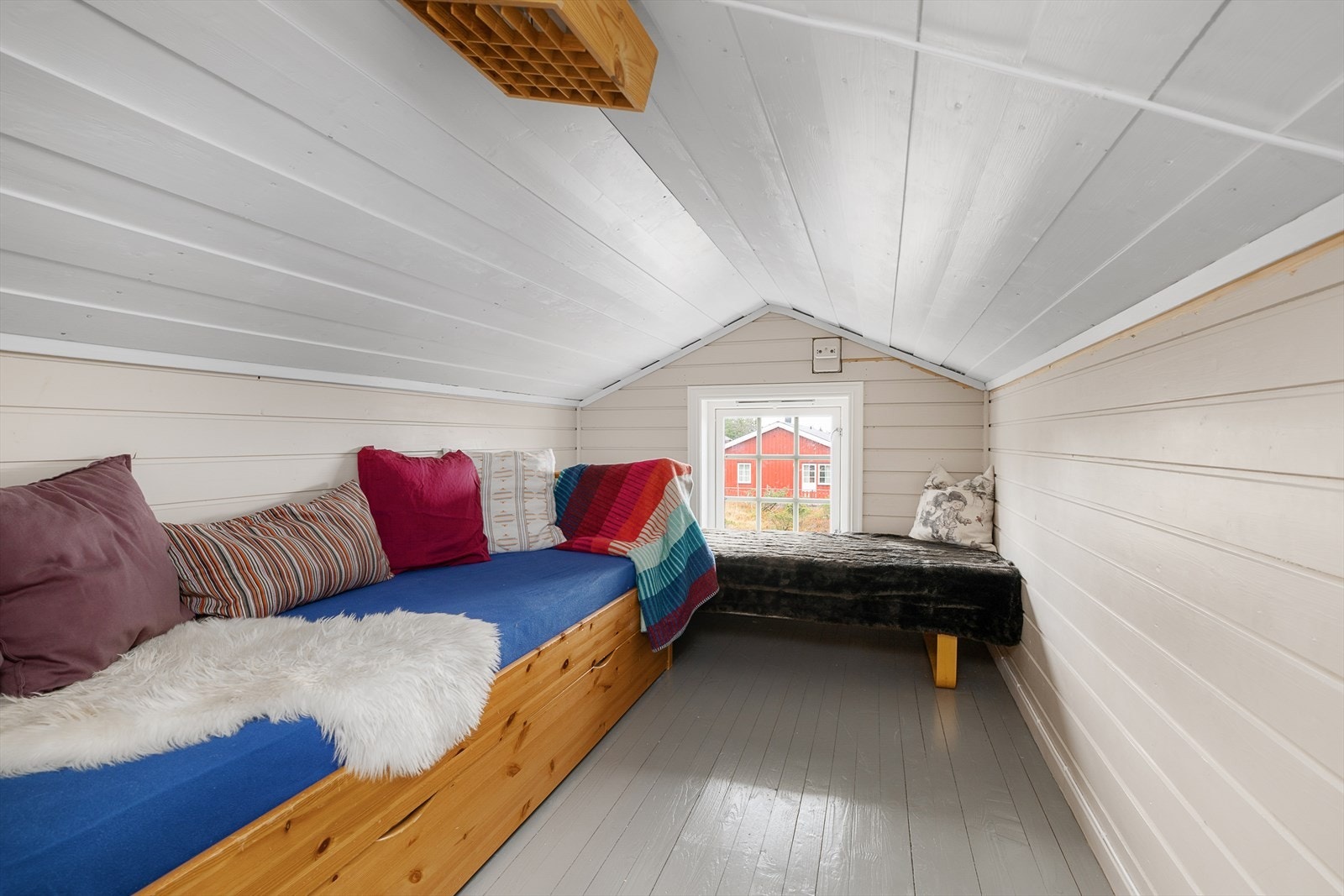 Bilde fra en koselig hems. Et lite vindu i gavlveggen slipper inn fint lys. Tak, vegger og gulv er malt. Galleribilde