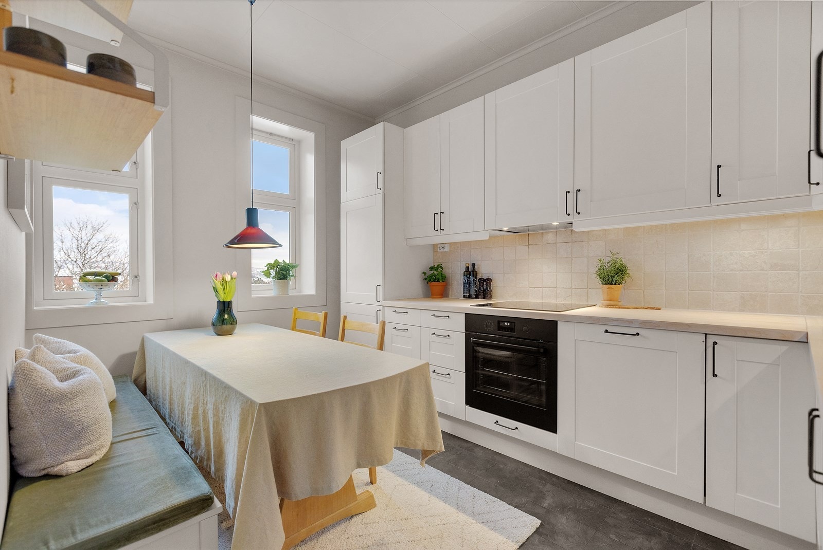 Tidløst kjøkken med glatt laminert kjøkkeninnredning, fliser mellom overskap og benkeplate i tre, kum med ettgreps blandebatteri. Galleribilde