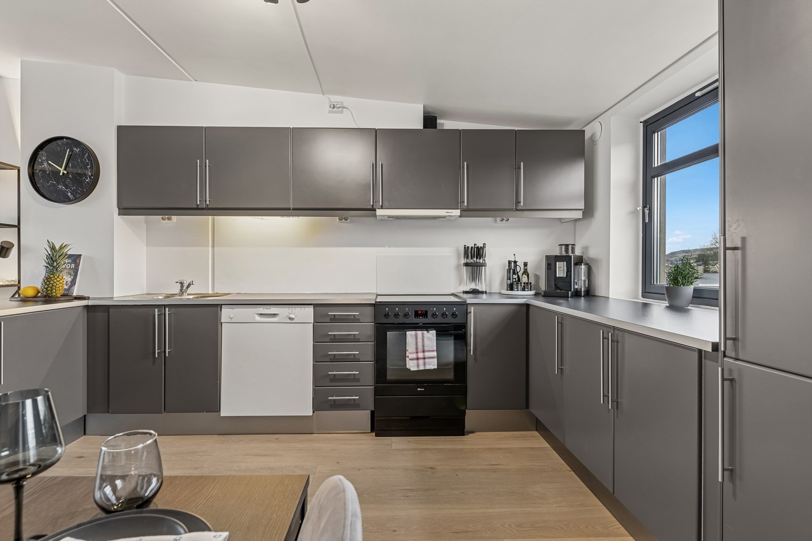 Kjøkkenet er tidløst innredet med grå, slette fronter og grå benkeplate i laminat. Et stort og godt kjøkken hvor man har rikelig med skap- og skuffeplass, samt gode arbeidsflater på benk. Galleribilde