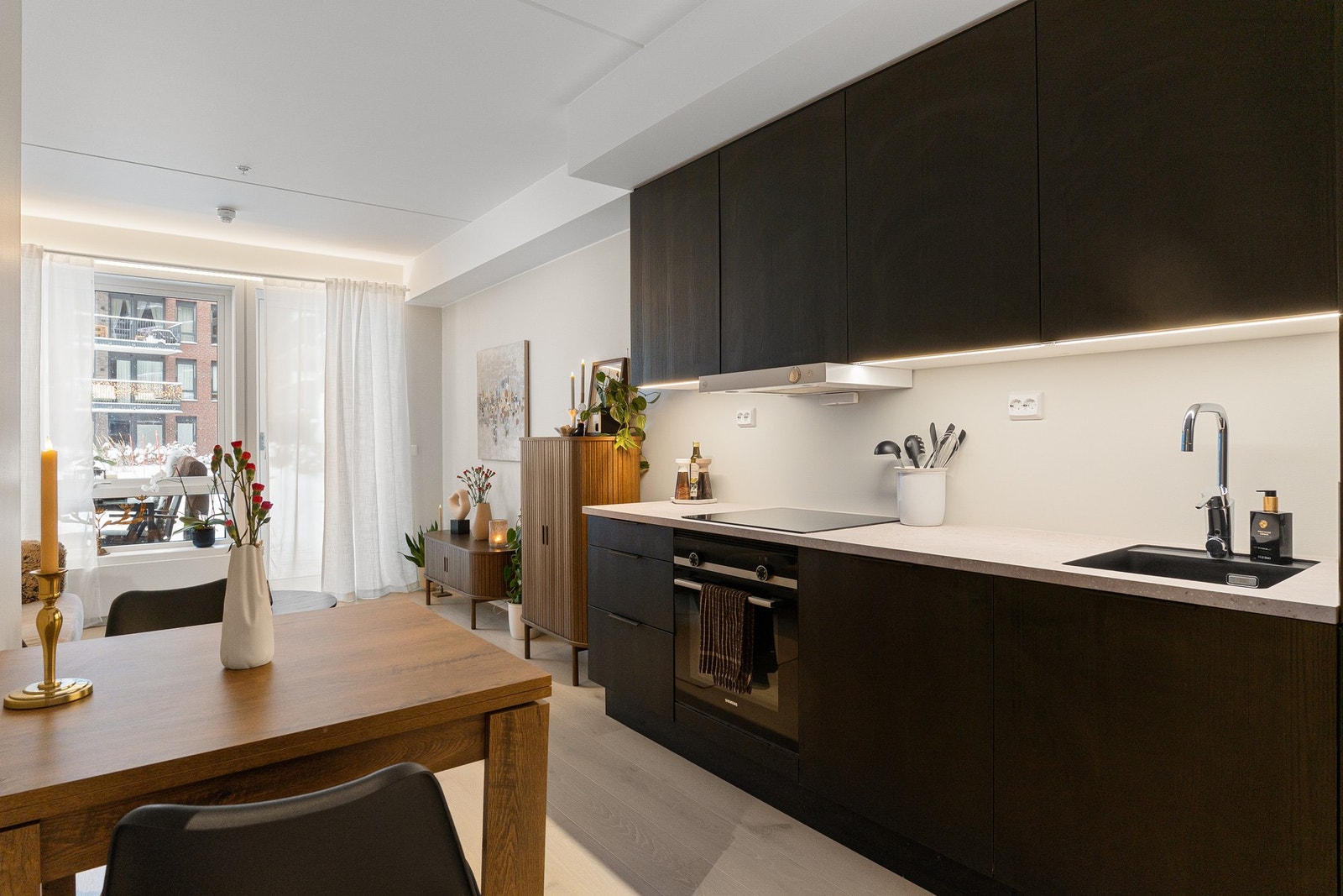 Åpen stue/ kjøkkenløsning. Kjøkkeninnredning med glatte fronter. Laminert benkeplate med nedsenket oppvaskkum og armatur. Galleribilde