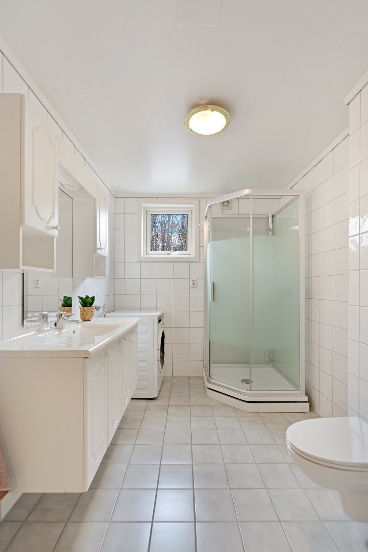 Badet er innredet med kabinett, vegghengt toalett, bidé, opplegg for vaskemaskin og god innredning med skap og speil Galleribilde