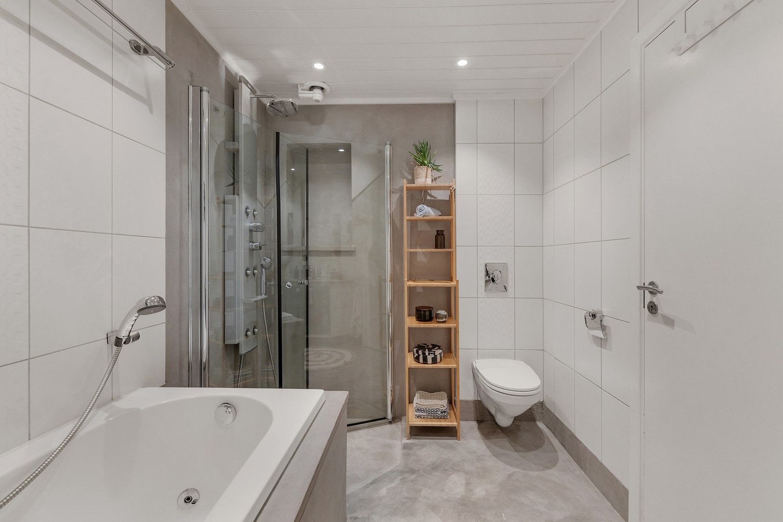 Pent og funksjonelt bad utstyrt med servant med underskap, vegghengt toalett, innbygget boblekar samt dusjsone med innfellbare dører. Galleribilde