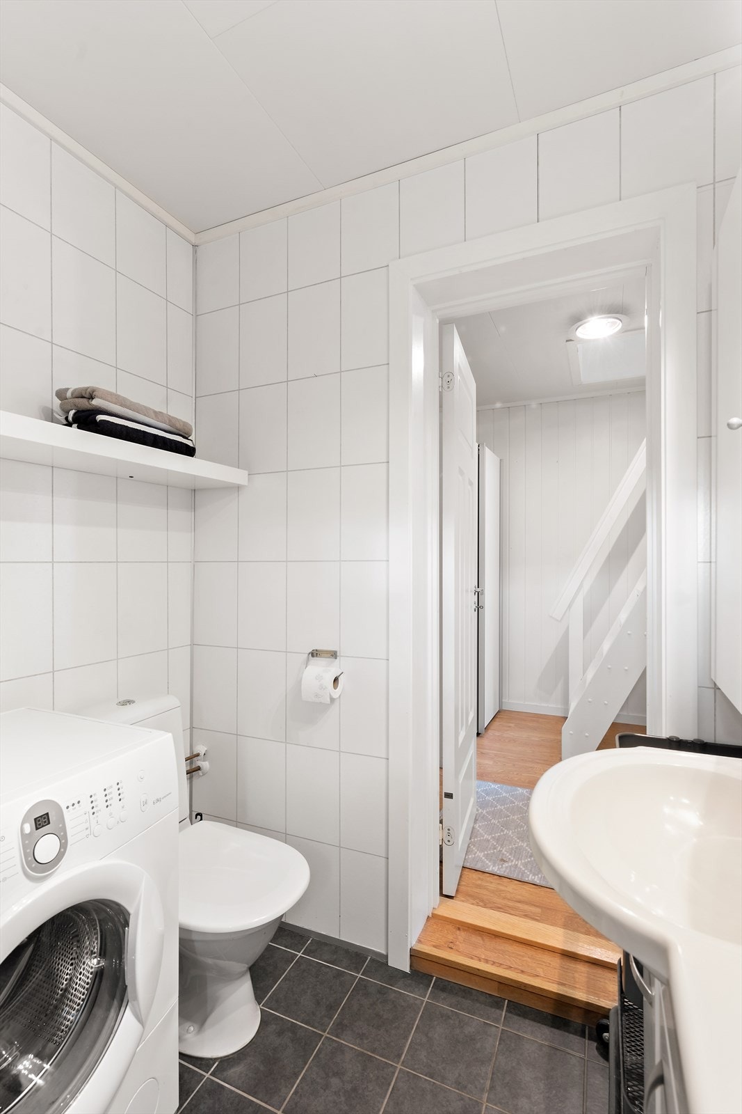 Rommet er innredet med toalett, servant med oppbevaring under, dusjkabinett og opplegg for vaskemaskin. Galleribilde