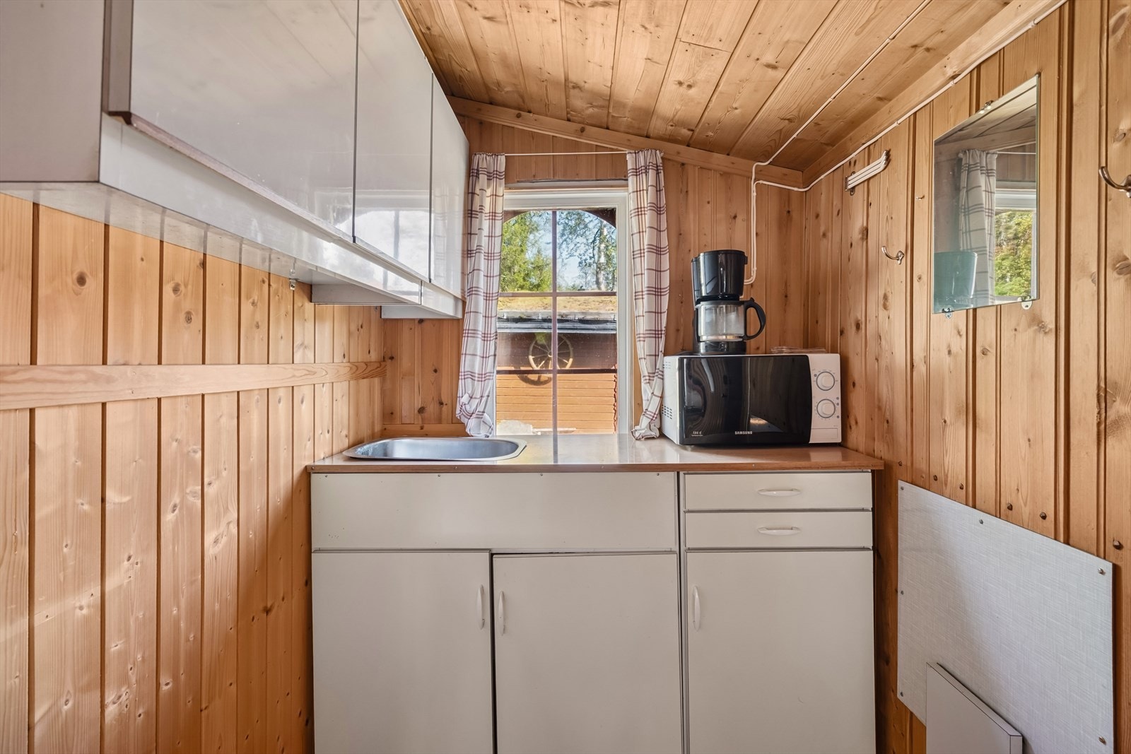 Kjøkkenet ligger i en alkove i stuen, og fremstår som praktisk og bruksvennlig. Innredningen har glatte fronter, med hvite overskap og beige benkeskap. Videre har kjøkkenet laminert benkeplate og nedfelt kum. Galleribilde