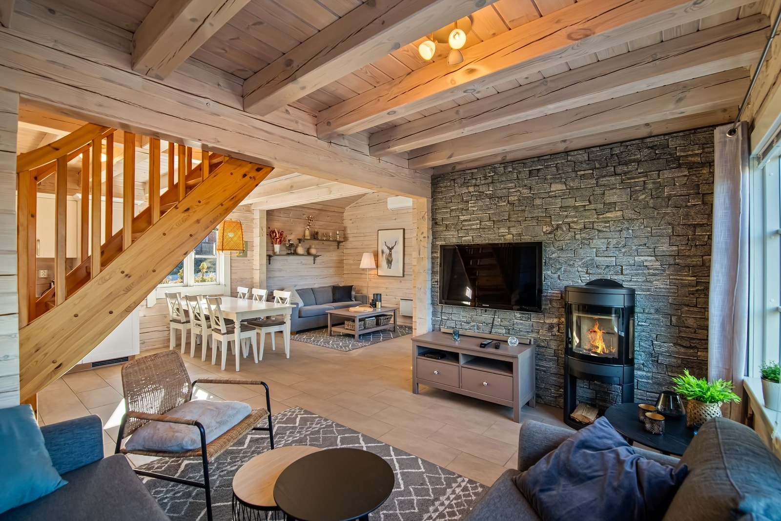 Delikat og tidløst innredet med lyse flisevalg, lysbeidede overflater og pen stenvegg i tv-stuen Galleribilde