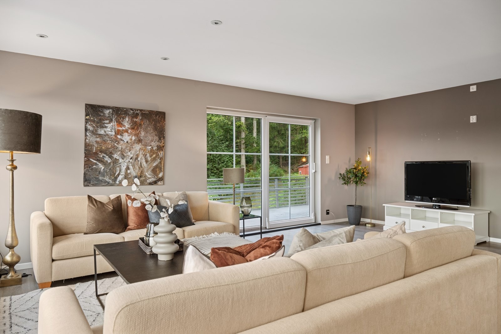 Fra stuen leder en skyvedør ut til en stor terrasse som omkranser store deler av boligen. Galleribilde