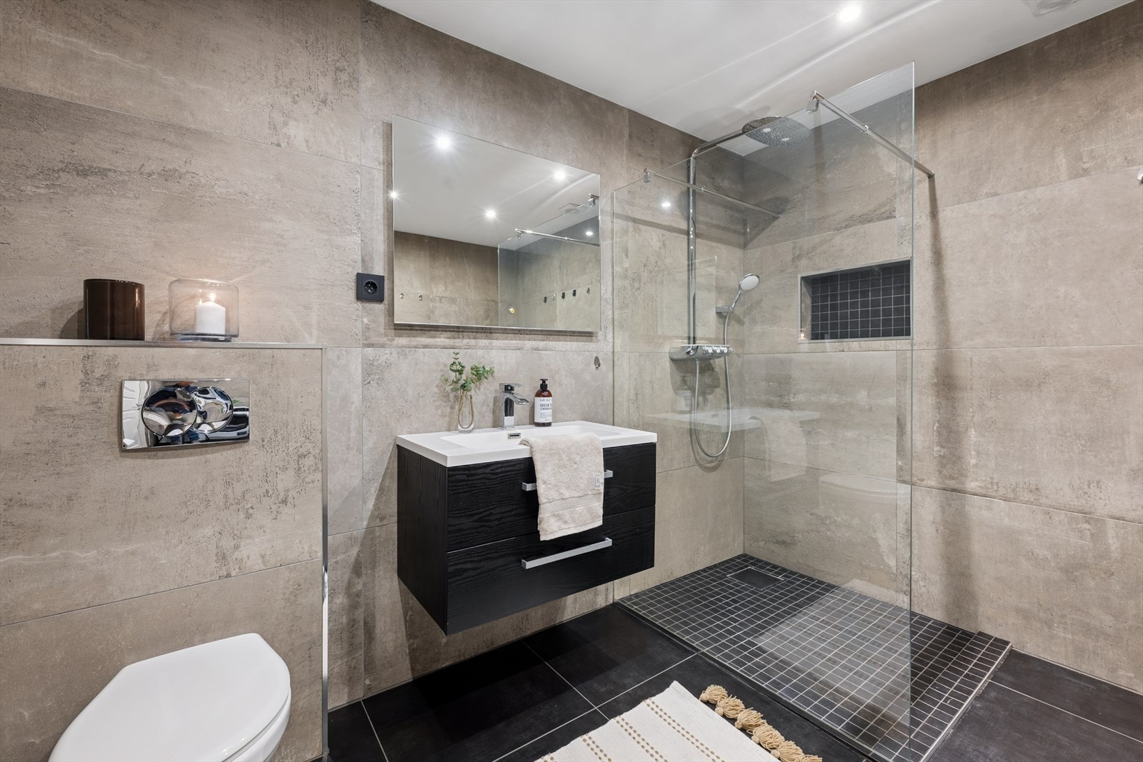 Innredningen består av speil, servant med seksjon, veggmontert toalett, dusjhjørne og opplegg for vaskemaskin. Galleribilde