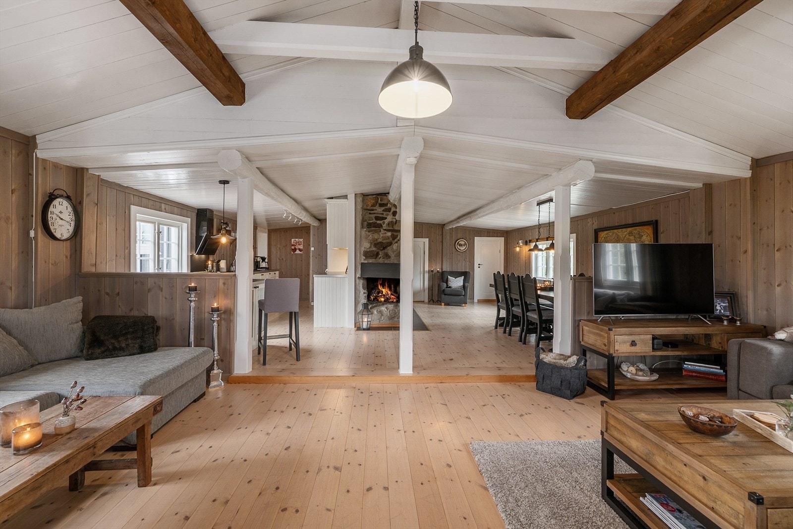 Koselig og moderne hytte med åpen planløsning, synlig trebjelker og en varm peis som skaper en innbydende atmosfære. Galleribilde