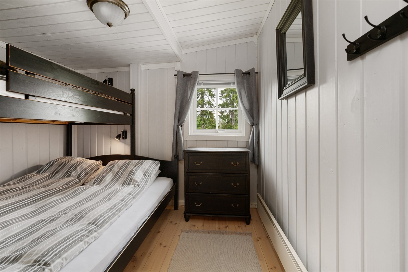 Soverom 1 innredet med familiekøye. Lysmalte vegger og tak. Tregulv. Plass til kommode under vinduet. Galleribilde