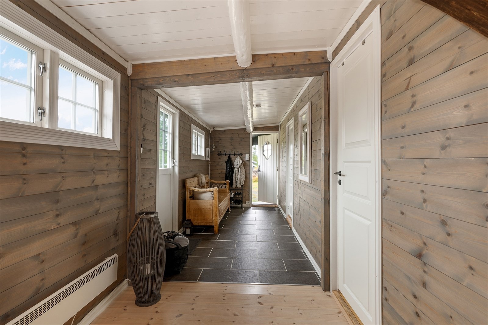 Hytta har en romslig inngang med flislagt gulv. Lune, panelte vegger. Galleribilde