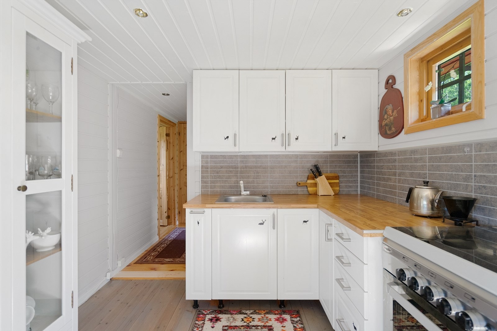 Koselig kjøkken i nøytral farge utstyrt med komfyr og kjøleskap Galleribilde