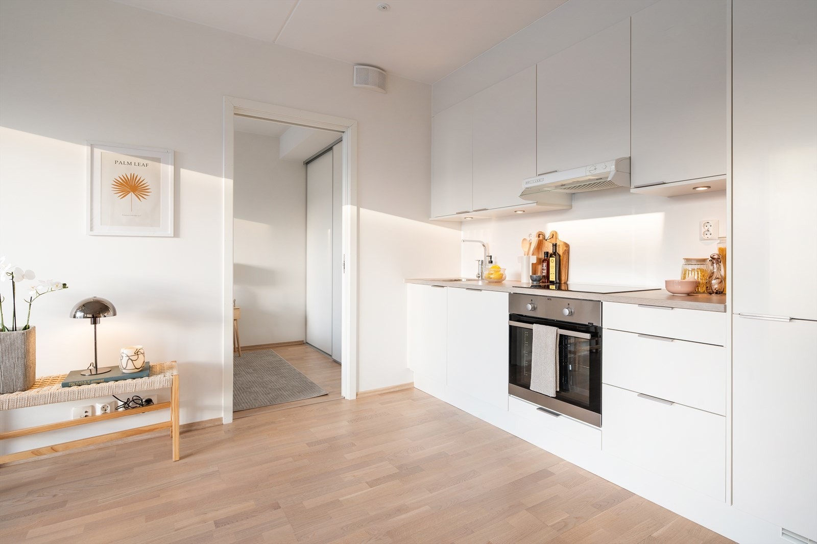 Lys og moderne innredning med integrerte hvitevarer (komfyr, platetopp, oppvaskmaskin og kjøl-/ fryseskap). Galleribilde