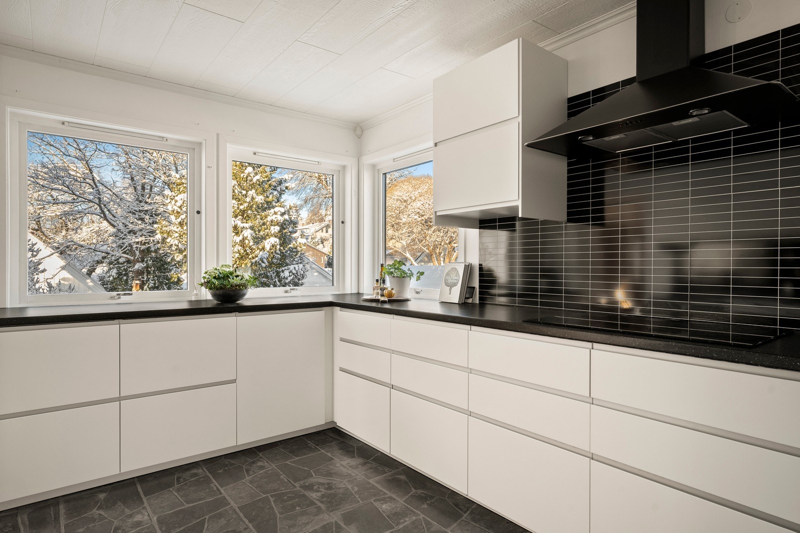 Det er montert beskyttelsesplater på vegg over benkeplaten på kjøkkenet. Ventilator plassert over platetopp med avtrekk ut. Galleribilde