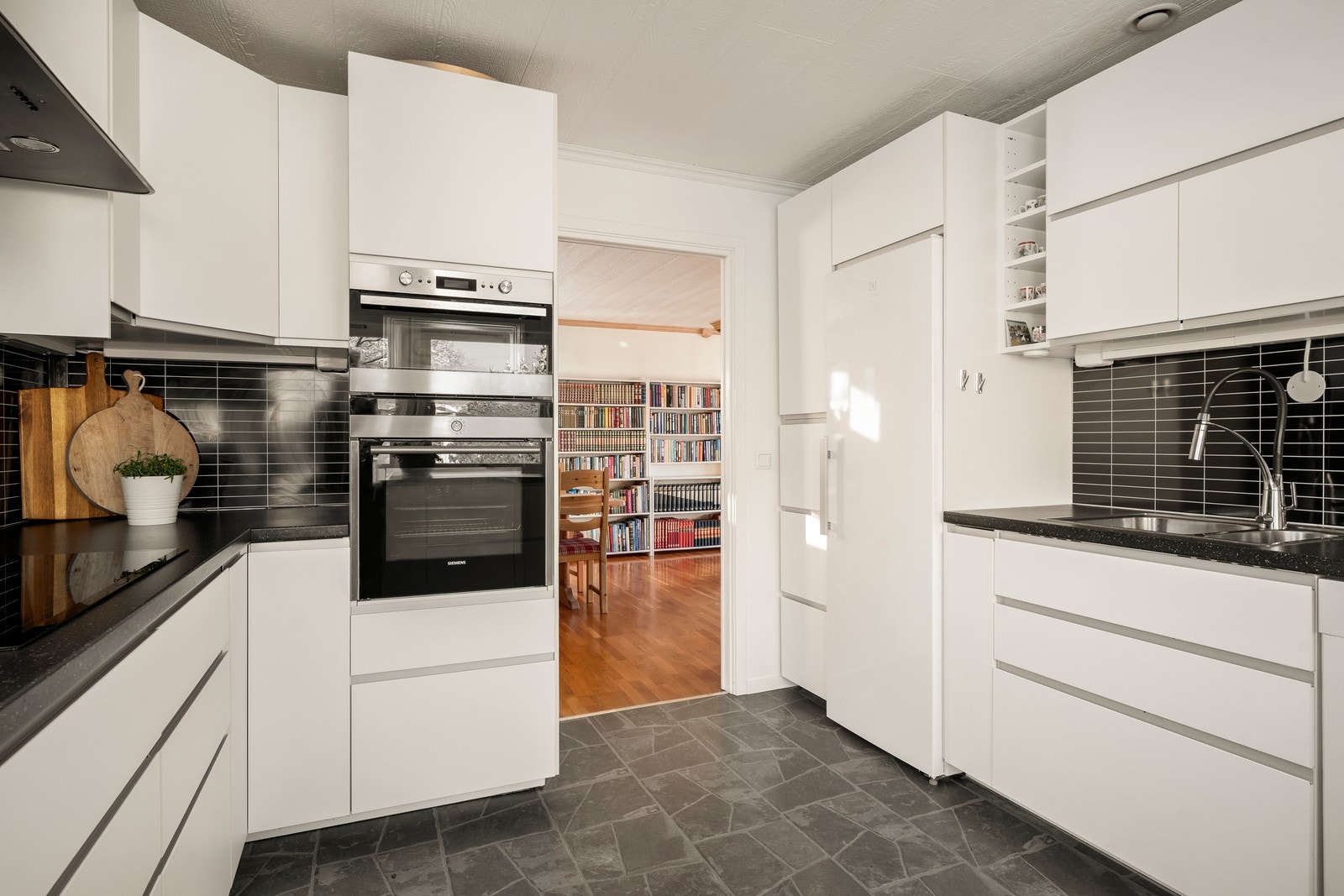 Kjøkkenet har en tilbaketrukket plassering og er praktisk innredet med glatte fronter, laminat benkeplate, nedfelt vask i rustfritt stål, kjøkkenarmatur og opplegg for oppvaskmaskin. Galleribilde