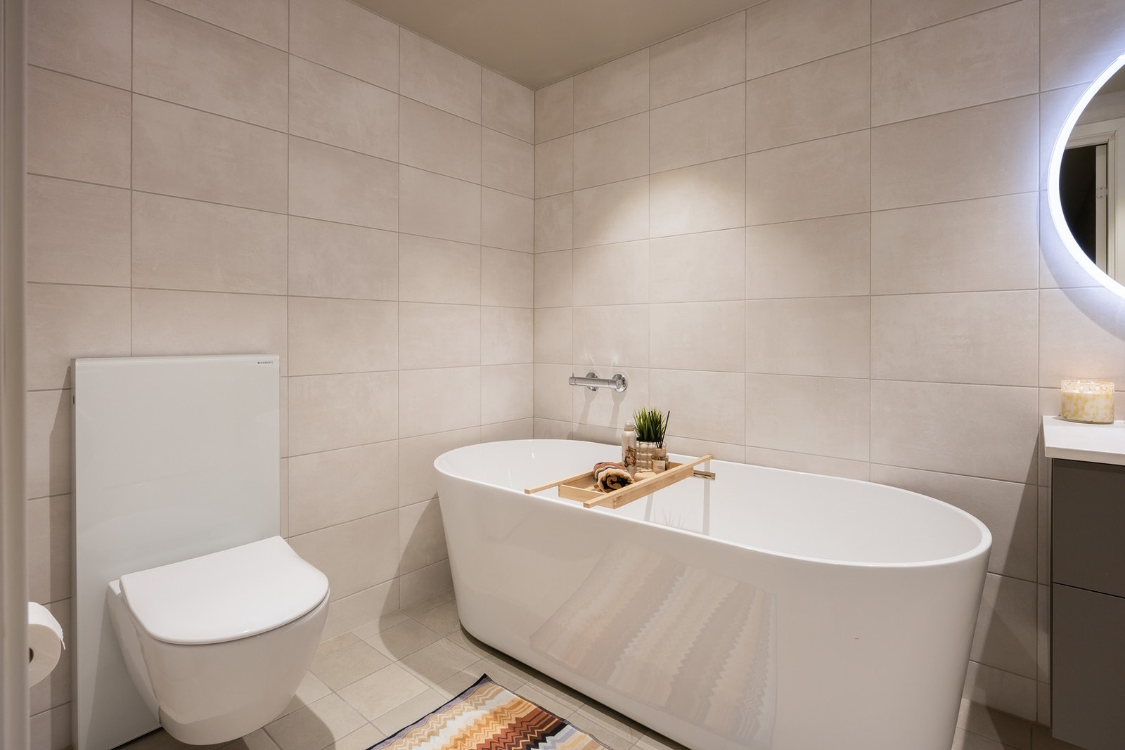 Badet fremstår moderne og stilrent, med flislagte overflater og varmekabler i gulvet. Galleribilde