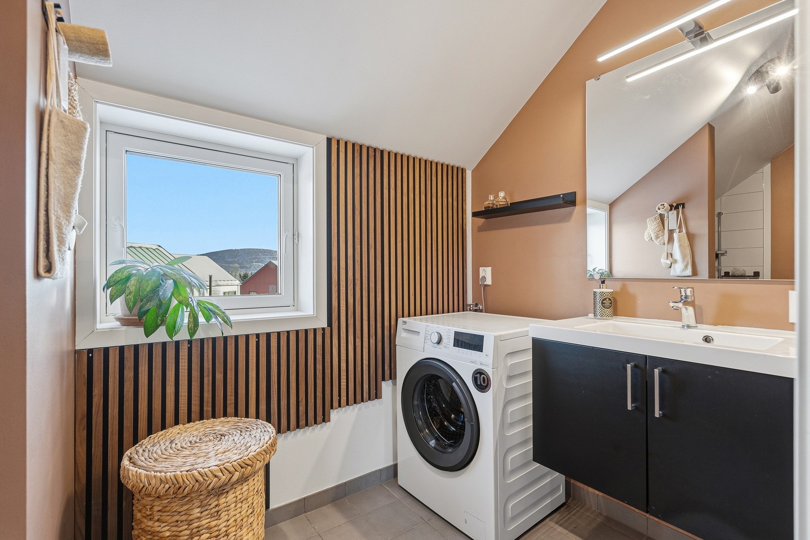 Etasjen inneholder også et romslig og pent bad, innredet med flislagt gulv med varmekabler, servantinnredning, veggmontert toalett og badekar. Galleribilde