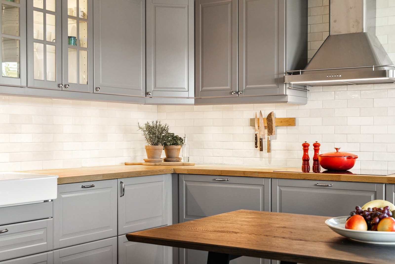 Innredningen har grå, profilerte fronter, vitrinedører, takhøye skap og gyllen, solid heltrebenkeplate. Galleribilde