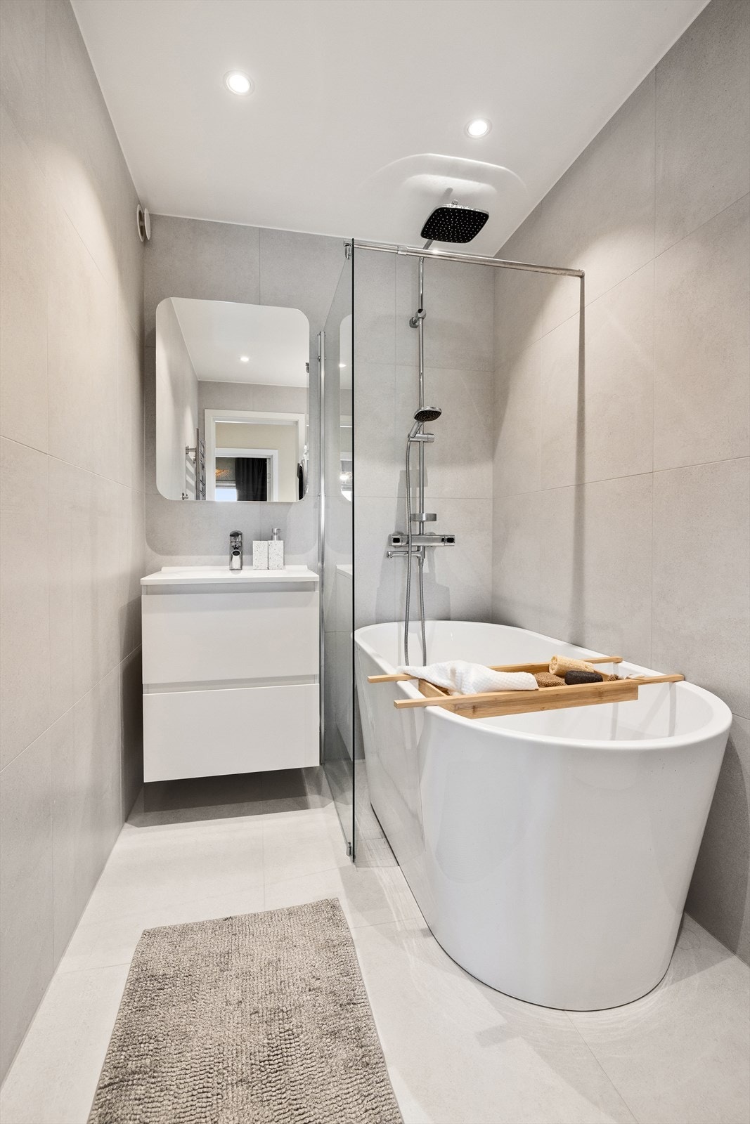 Dusjhjørne med fast glassfelt og dusjarmatur tilkoblet regndusj og hånddusj, og badekar ved dusj. Galleribilde