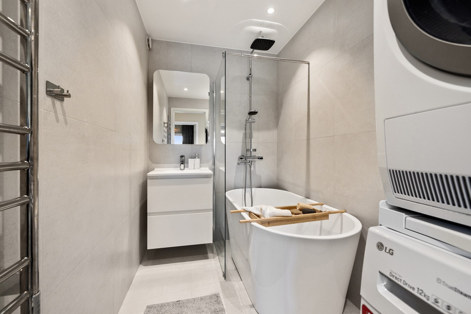 Innredet med vegghengt servantinnredning med glatte fronter og heldekkende servant med ett-greps armatur, speilskap over servant, og håndkletørker. Galleribilde