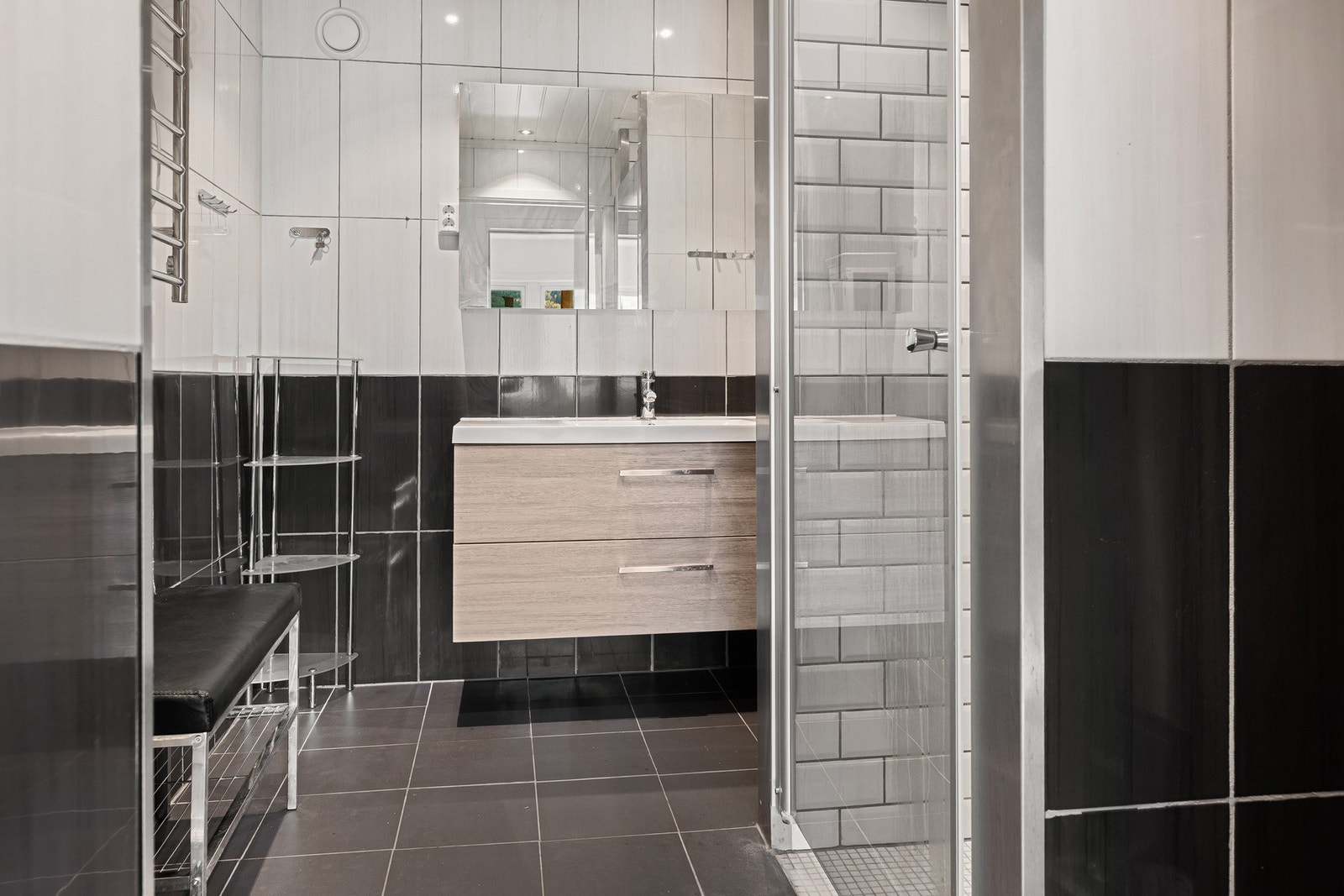 Flislagt bad utstyrt med heldekkende servant med skuffer samt dusjnisje. Galleribilde