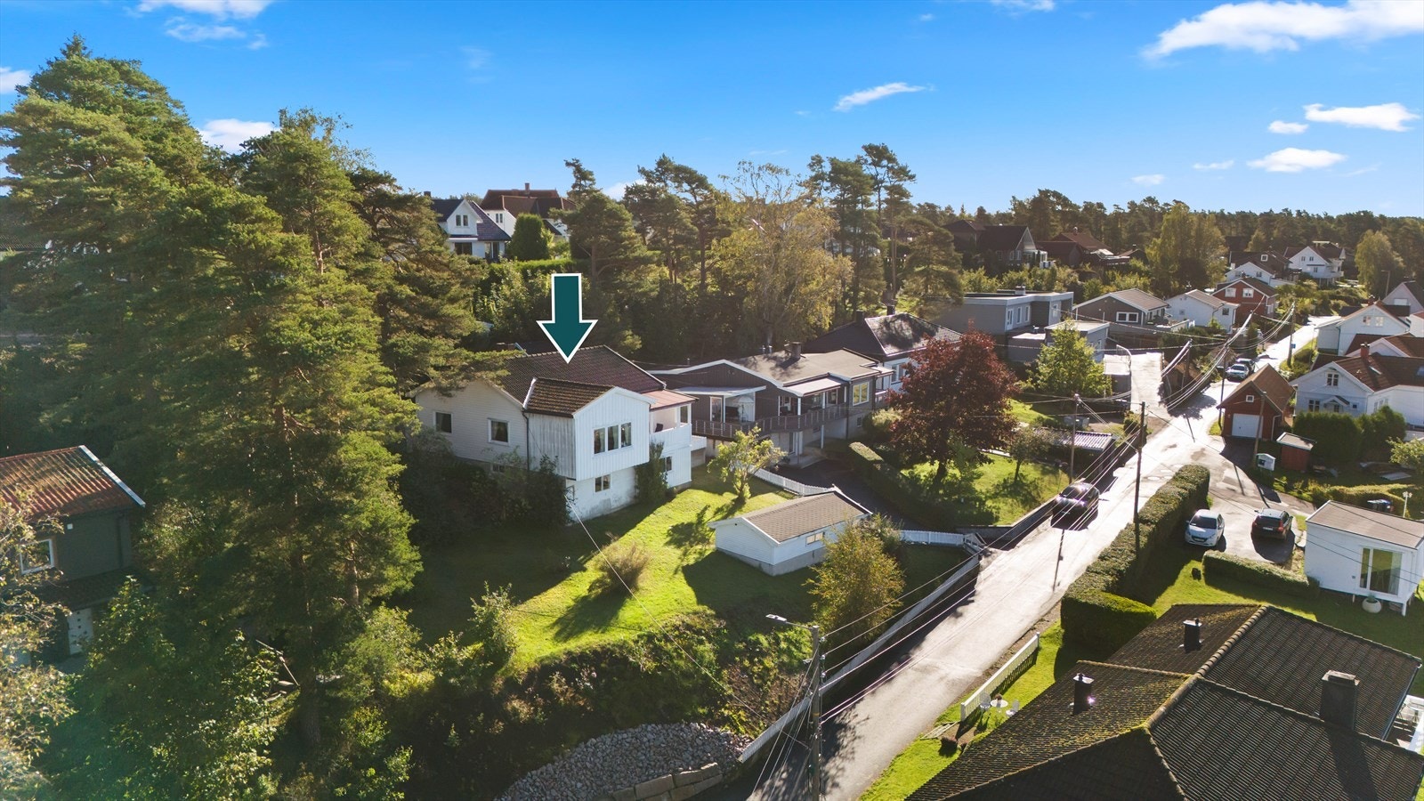 Romslig hage med plen og beplantning. Det er asfaltert innkjørsel med frittstående garasje på tomten. Galleribilde