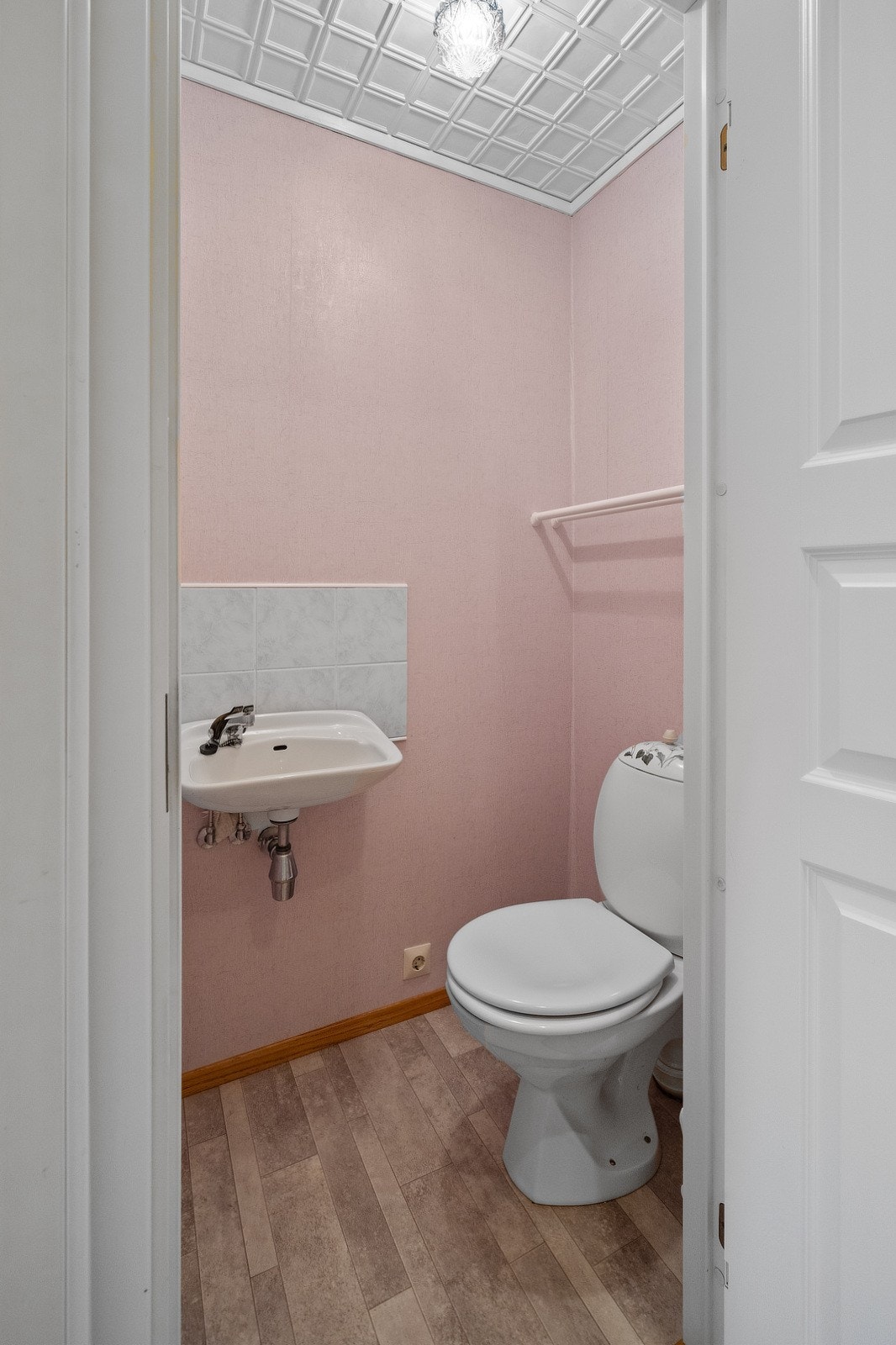 Boligen har separat toalett med adkomst fra entréen med porselensvask på vegg med 2-greps blandebatteri og gulvstående toalett. Galleribilde