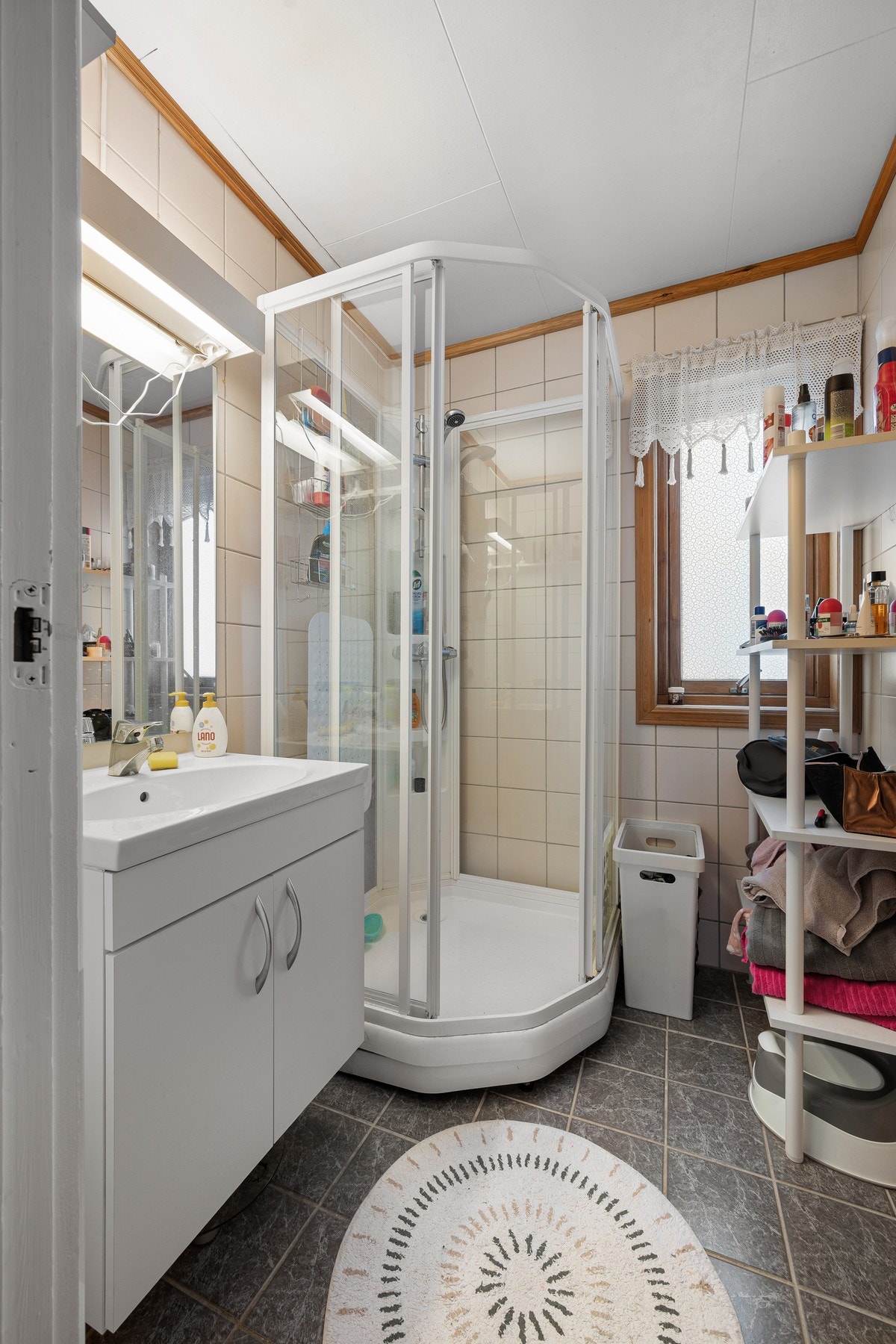 Bad med flislagte overflater og inneholder servantinnredning og dusjkabinett Galleribilde