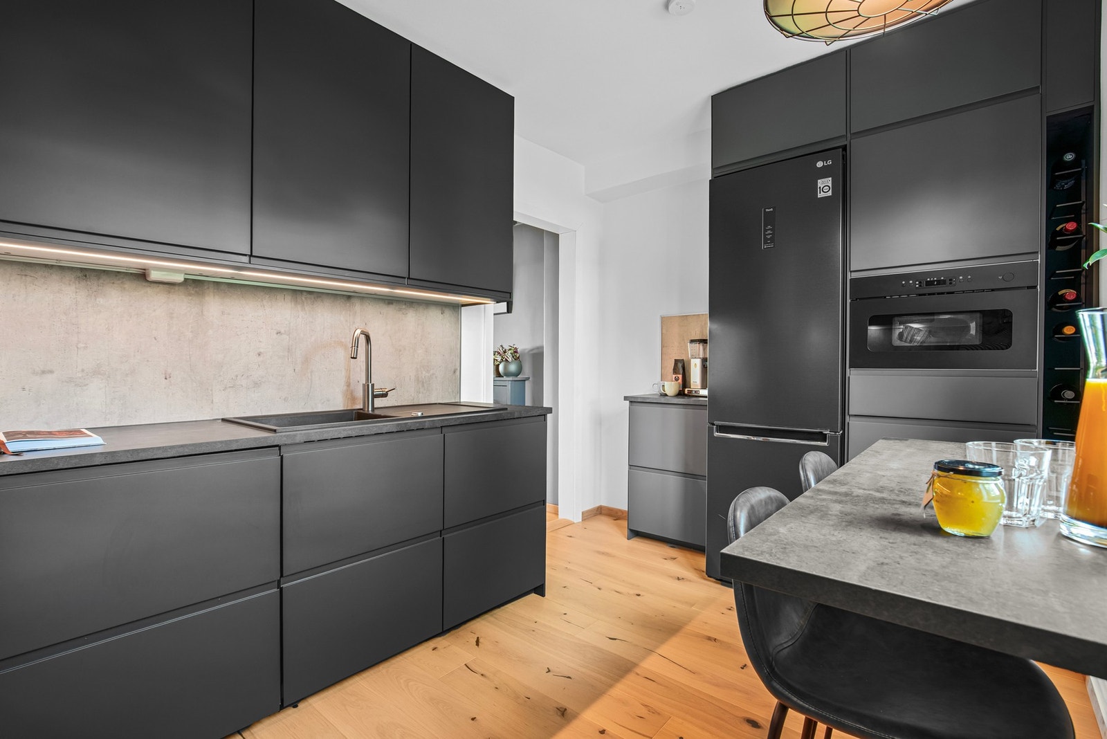 Innredningen er fra IKEA, med mørkegrå, glatte fronter, vinhyller, benkeplate av laminat og nedfelt oppvaskkum i kompositt. Galleribilde