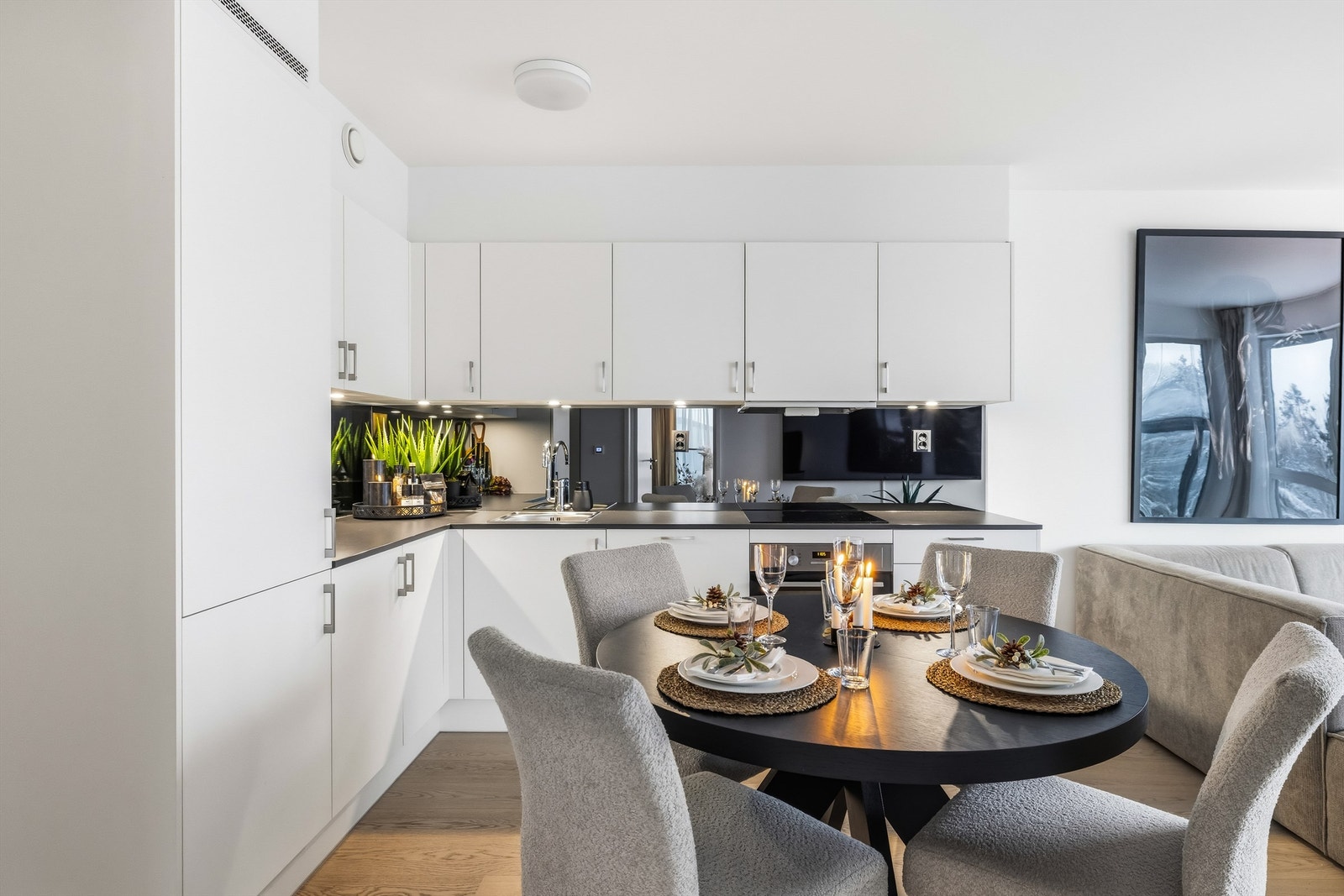 Kjøkkenet har stilren innredning med glatte fronter, laminat benkeplate og sotet speil mellom benkeplate og overskap. Integrerte hvitevarer. Galleribilde