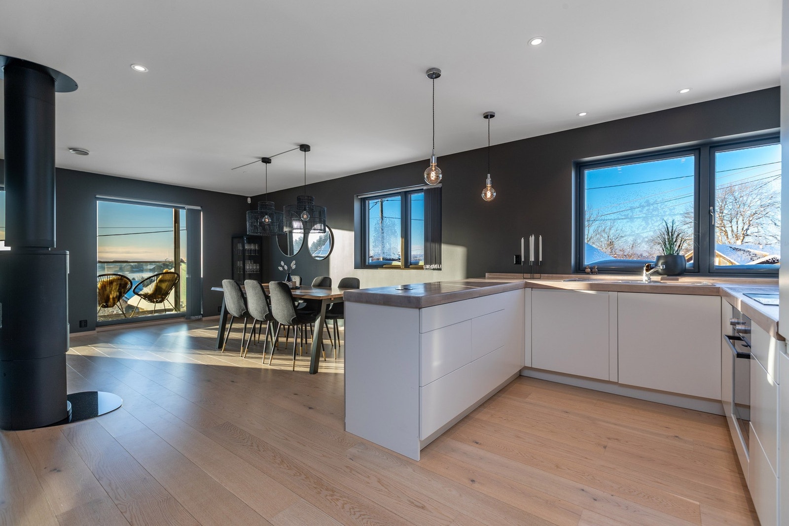 Kjøkken/spisestue/dagligstue i vinkel m/peis, store glassflater og utsikt Galleribilde