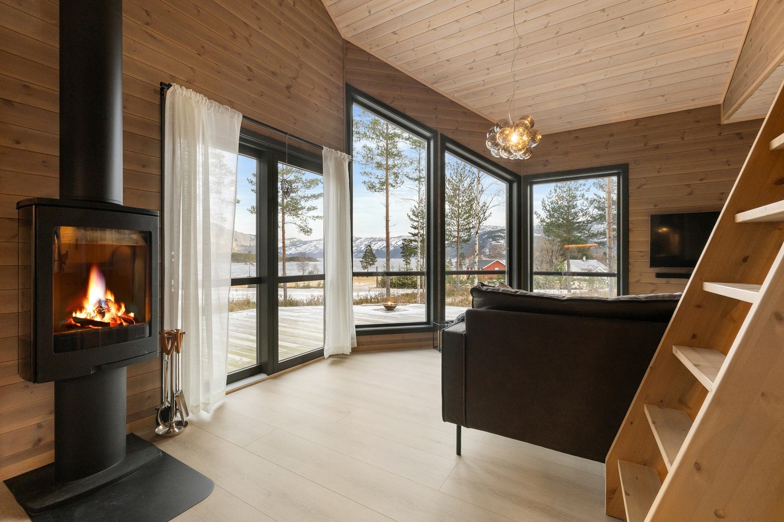 Stuen er et naturlig samlingspunkt i hytta, med åpen løsning mot kjøkken og imponerende takhøyde som gir en luftig og innbydende romfølelse. Galleribilde