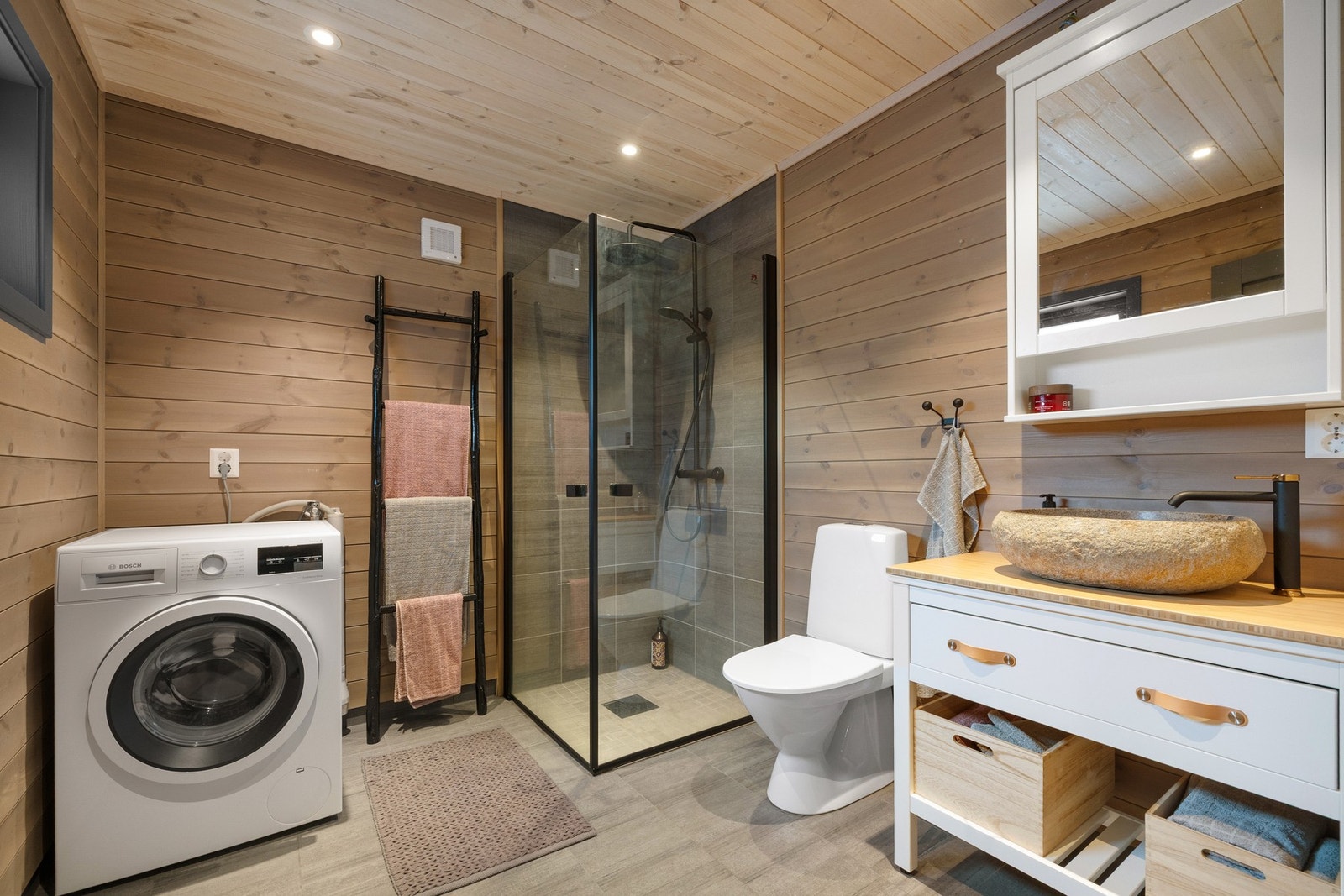 Badet er utført med fliser på gulv og i dusjsonen, mens øvrige vegger og himling har panel. Galleribilde