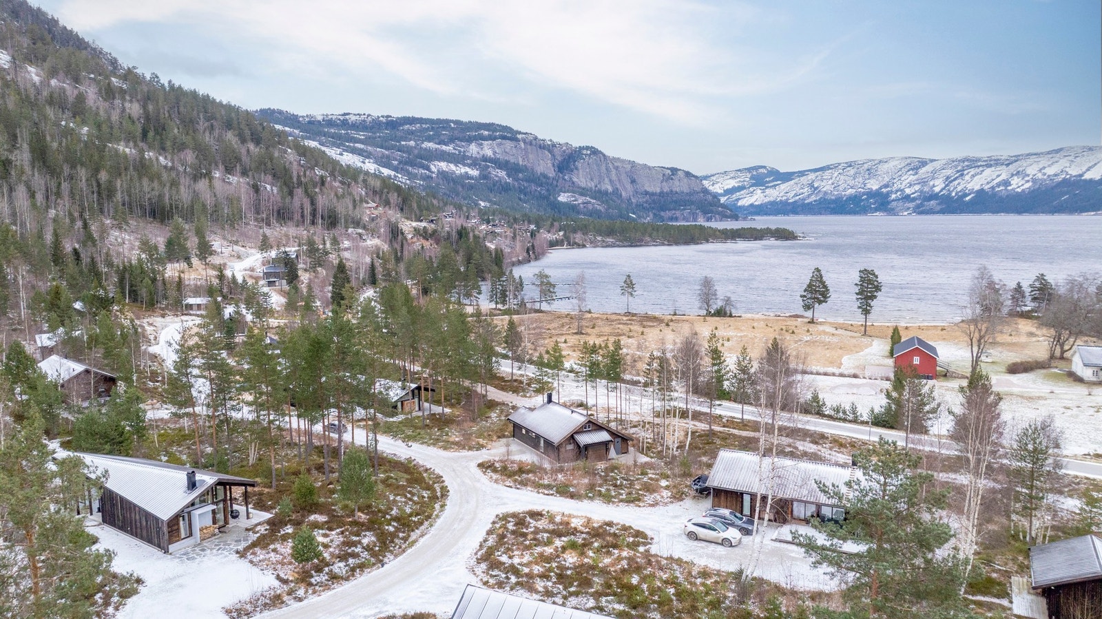 Oversikt over hyttefeltet med spredt bebyggelse, omgitt av skog og fjellterreng. Galleribilde